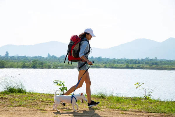 young woman with backpack hiking with dog on mountain river. active lifestyle, hiking and travel concept