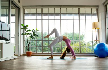 Asya 'lı kadın yoga sonrası yoga yapıyor ve oturma odasında dergi okuyor. Evde Tayland egzersizi..