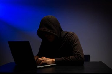 Siber saldırı, kişisel veri ve şifre kırma programı ile bilgi çalıyor. Hacker arama ve saldırı sistemi için dizüstü bilgisayarıyla klavye yazıyor.