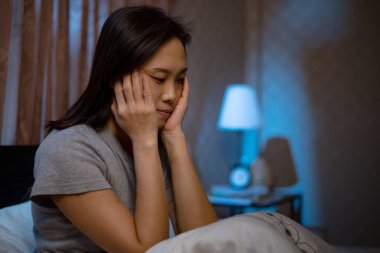 Depresyondaki Asyalı kadın yatakta uyuyamaz. Uykusuzluk sendromu mutsuzluktan sonra uykusuzluk çeker ve yaşam tarzı hakkında endişelenir. Üzüntü hisseder..