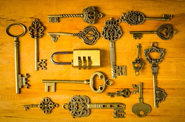Multiple vintage keys and combination lock  on wood board.