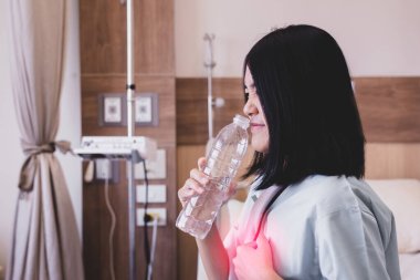 Asian woman patient having or symptomatic reflux acids at hospital,Gastroesophageal reflux disease,Drinking water clipart