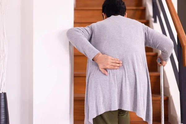 Senior older woman suffering from low-back lumbar pain while walking on stair at home,Low back pain lumbar backache