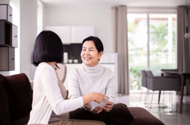 Kızım evde birlikte kanepede otururken annesine doğum günü kartı veriyor. 