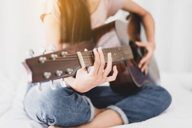 Evde yatarken gitar çalan elleri olan kadın, eğleniyor.