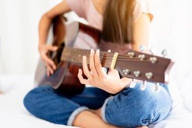 Evde yatarken gitar çalan elleri olan kadın, eğleniyor.