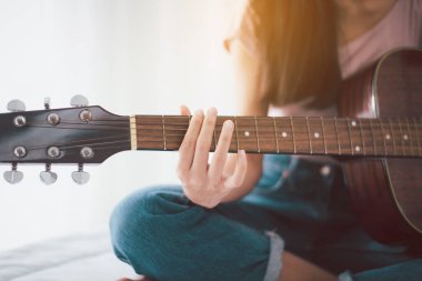 Evde yatarken gitar çalan elleri olan, eğlenen kadınlar.