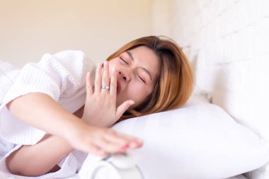 Tembel kadın yatakta esniyor ve uykulu, uykulu kadın semptomlar gösteriyor.