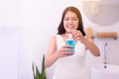 Tuvalette ağız çalkalamak için gargara kullanan kadın, taze nefes, diş sağlığı konsepti.