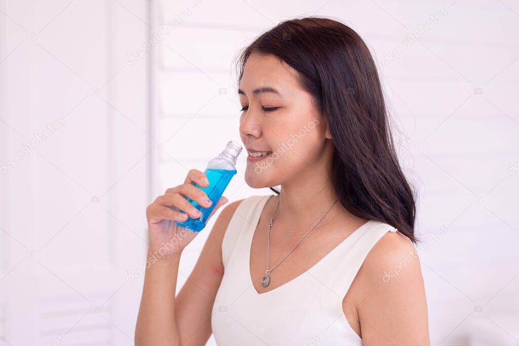 Woman using mouthwash to rinsing mouth in restroom,Fresh breath,Dental health care concept
