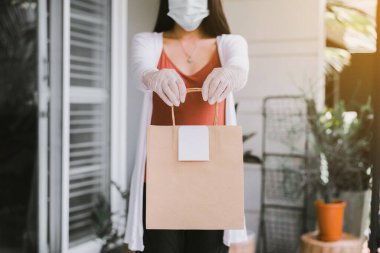 Coronavirus salgını sırasında elinde paket yiyecek olan bir kadın.