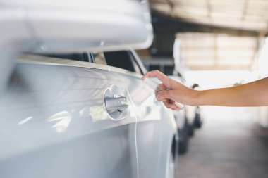 Kadın, kapı koluna alkol sıkarak Coronavirüs, Covid-19 salgınına karşı önleyici önlemler alıyor.