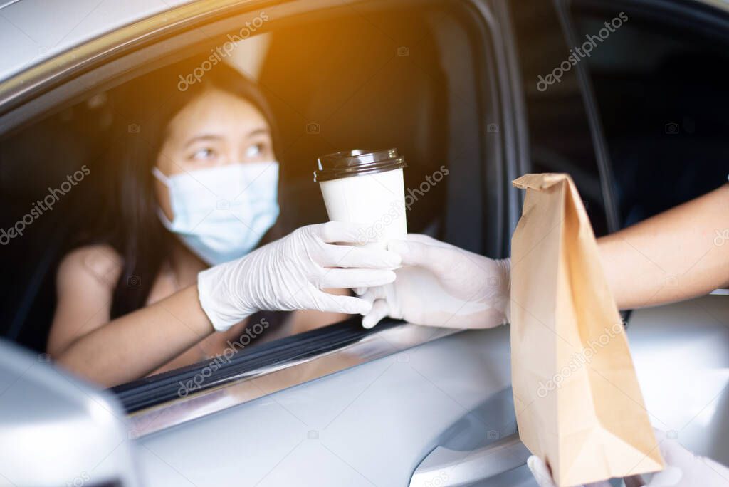 Food delivery courier give coffee cup to woman in her car,Safety food during coronavirus pandemic situation