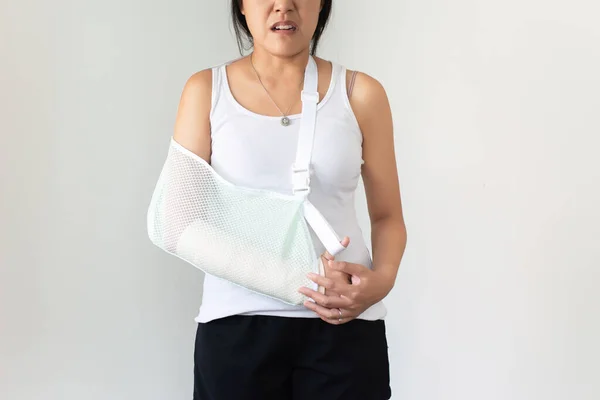 Patient woman wearing arm sling for relieve broken arms at home