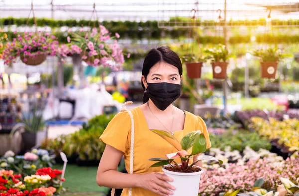 在花园中心佩戴外科口罩及购买植物的妇女 — 图库照片