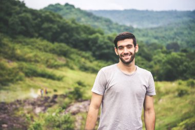 Dışarıda duran sakallı, mutlu ve gülümseyen, seyahat eden yakışıklı bir adamın portresi.