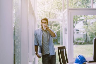 Mimar adam modern ofiste kahve içiyor, mutlu ve gülümsüyor.