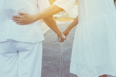 Yaşlı Asyalı kadın parkta sopayla fiziksel temasta bulunmak için yürüyor.