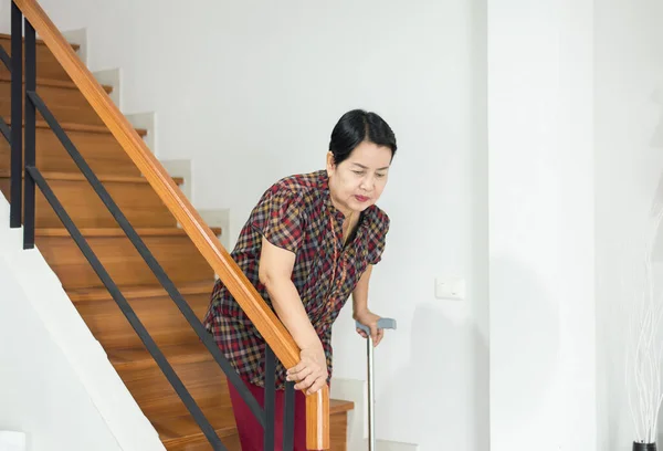 高齢のアジアの女性は家で階段を下りながら棒を保持 — ストック写真