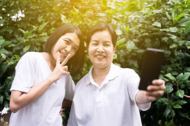 Cep telefonlu Asyalı kadın selfie 'si, doğanın tadını çıkarıyor.