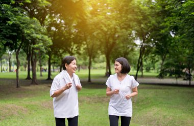 Sabahın erken saatlerinde kızı ile birlikte parkta koşan yaşlı Asyalı kadınların portresi, sağlıklı ve dikkatli olun.