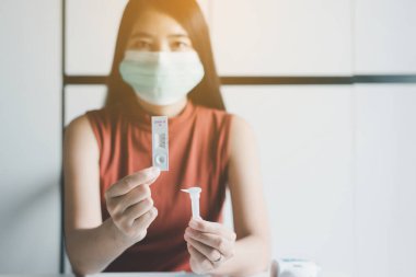 Asyalı hasta kadın, evinde kendi kendini test eden bir covid-19 kullanıyor.
