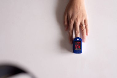 Parmak ucu nabız oksimetre oksijen doygunluk ölçer kullanan hasta kadın beyaz arka planda SPO2 PR kan monitörü parmağı