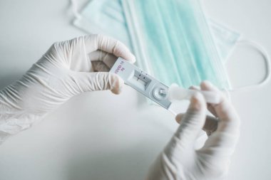 Doktor kadın sonuçlara göre evde kendi kendini test eden hızlı bir antijen test kiti var.