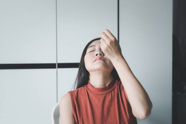 Hasta Asyalı kadın, evinde kovid 19 testi için burun temizleme bezi ve hızlı antijen testi yapıyor.