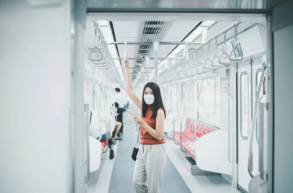 亚洲妇女戴着面具 在地铁列车上使用智能手机 公共交通安全 Covid 19大流行期间的新常态 — 图库照片