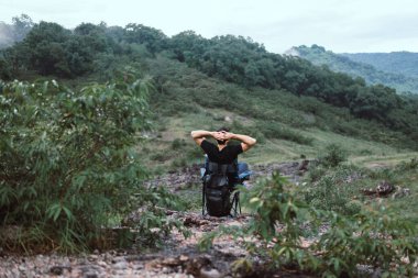 Kamp yapmaktan hoşlanan genç adam manzaraya bakıyor ve sandalyeye oturuyor. Mutlu ve doğaya gülümsüyor.