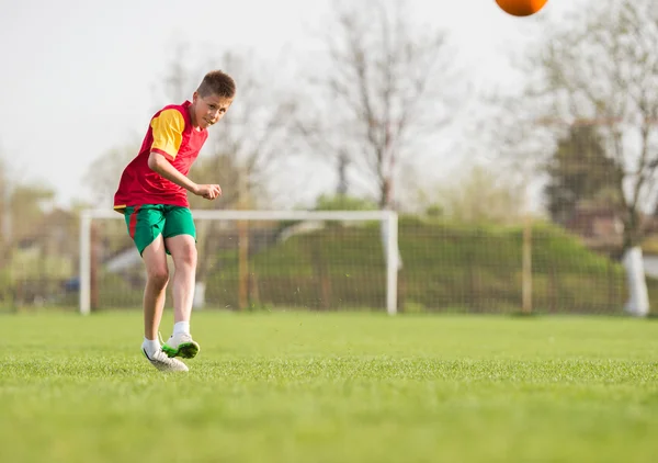 Kind kickt einen Fußball — Stockfoto