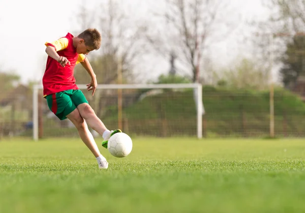 Pojken sparkar en boll på mål — Stockfoto