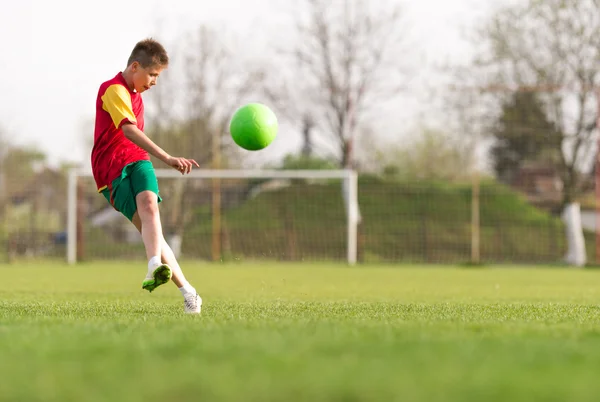 Menino chutando uma bola no gol — Fotografia de Stock