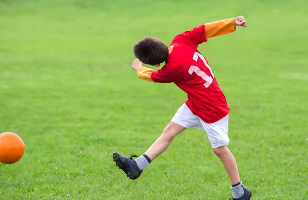 Gutt som sparker en fotball – stockfoto