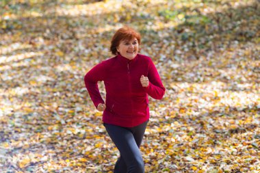 Aktif orta yaşlı kadın doğada koşuyor.