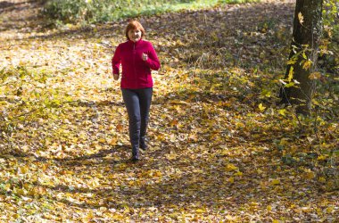 Aktif orta yaşlı kadın doğada koşuyor.