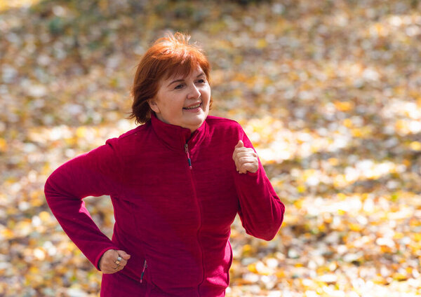 Active middle-aged woman  jogs runs on nature
