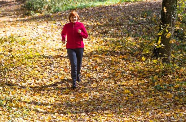 活跃的中年女性慢跑者在大自然中奔跑 — 图库照片