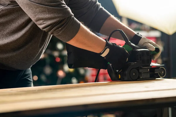 Carpenter works with belt sander in carpentry