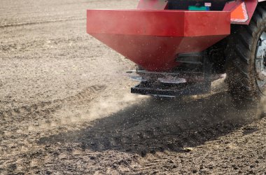 Traktör alana yapay gübre yayıyor.