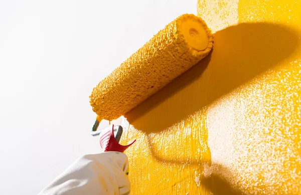 ローラーと黄色の塗料で壁を描く女性の写真 — ストック写真