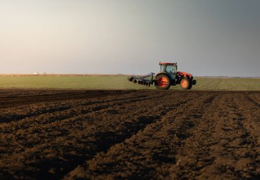 Traktör sürme çiftliği akşam yeni ekin ekimi için toprağı hazırlıyor..