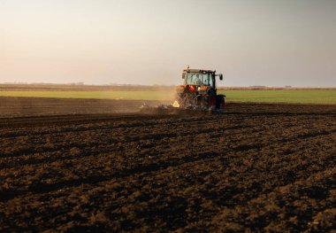 Traktör sürme çiftliği akşam yeni ekin ekimi için toprağı hazırlıyor..
