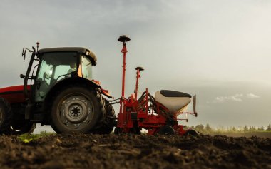Traktör tohumu eken bir çiftçi. Tarım tarlasına ekin ekiyor. Bitkiler, buğday.