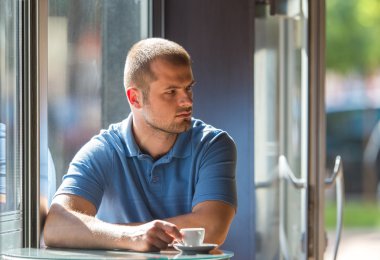 Genç adam kahve içiyor.