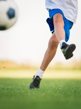 Kafkas bir çocuk futbol oynuyor ve topa vuruyor.