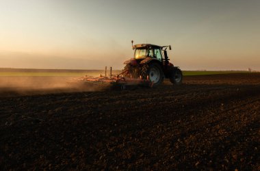 Traktör sürme çiftliği akşam yeni ekin ekimi için toprağı hazırlıyor..
