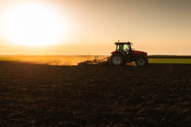 Traktör sürme çiftliği akşam yeni ekin ekimi için toprağı hazırlıyor..