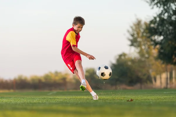 Garoto chutando uma bola de futebol — Fotografia de Stock